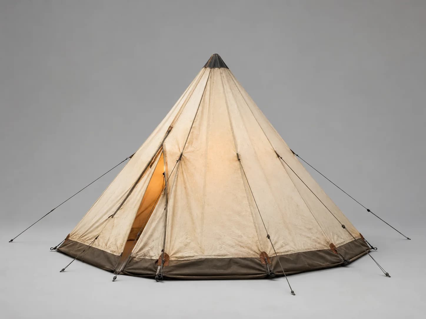 Prop card — canvas bell-style expedition tent guyed out on a neutral studio backdrop, warm interior glow showing through the canvas.